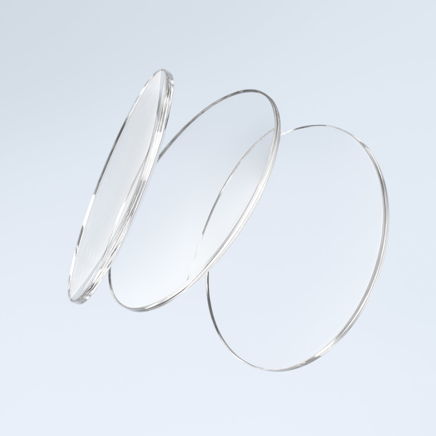 Drei transparente, schwebend dargestellte Brillengläser in unterschiedlichen Winkeln vor einem hellen, minimalistischen Hintergrund.